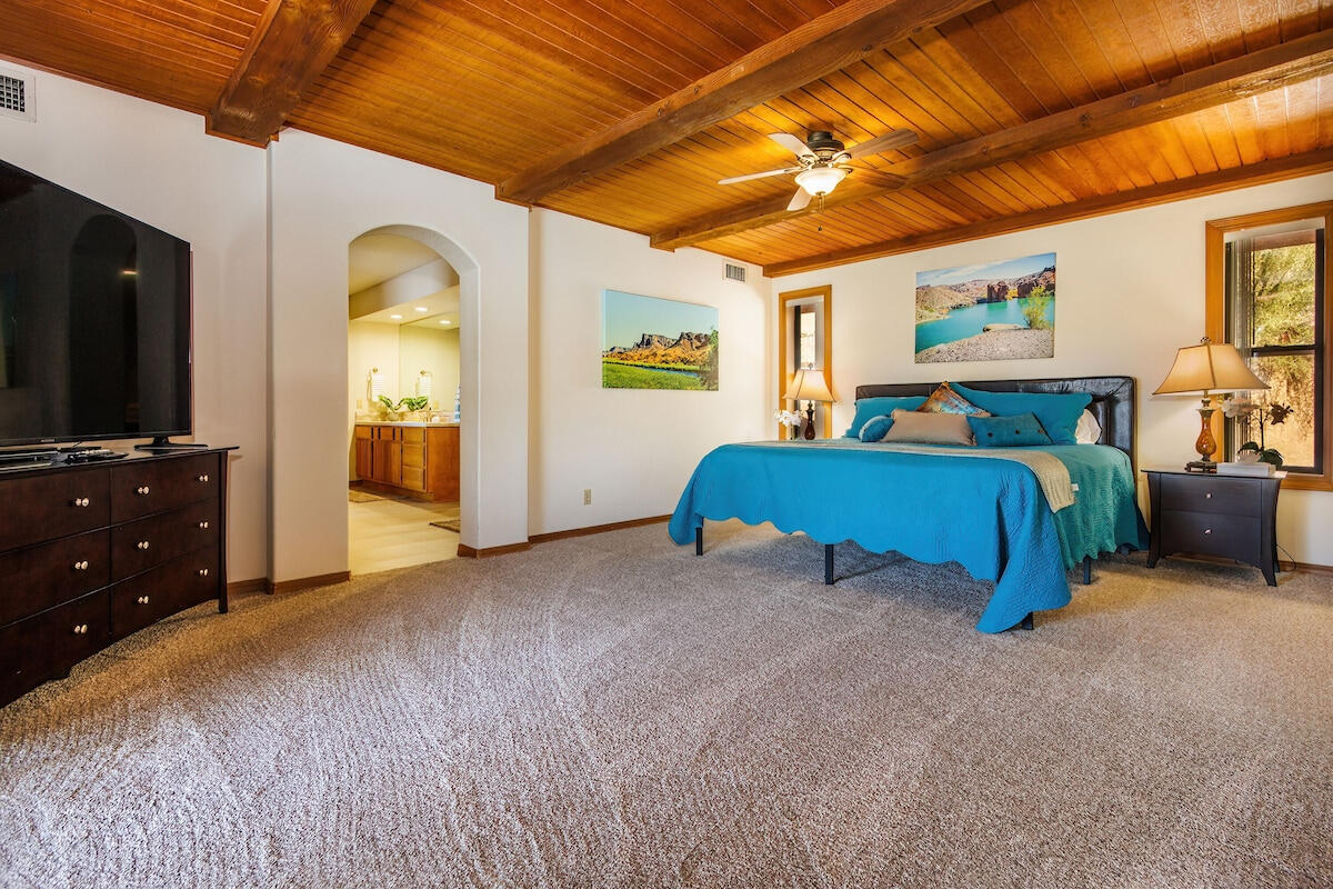 Lakeview Lodge Primary Bedroom with Wood Beam Ceiling Primary bedroom at Lakeview Lodge vacation rental in Lake Havasu City Arizona with king bed, wood beam ceiling, TV and ensuite access