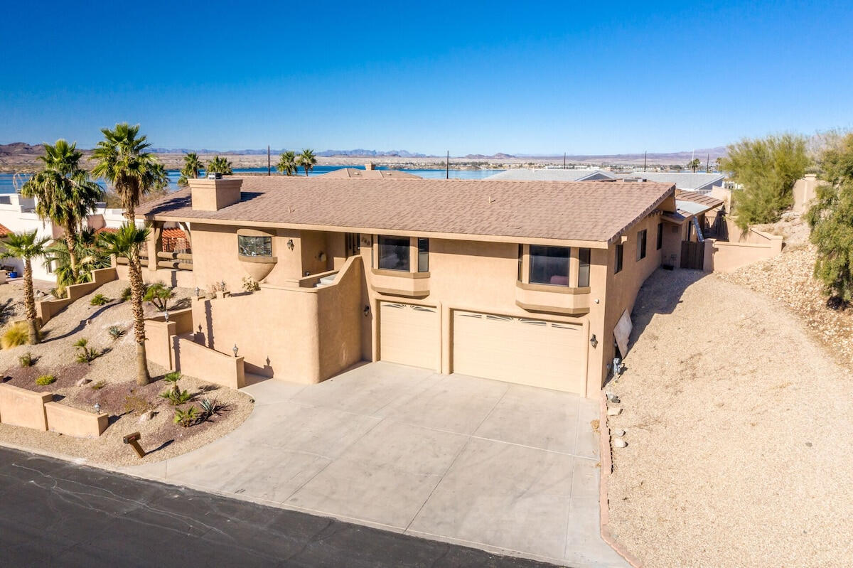 Front exterior of Lakeview Lodge vacation rental in Lake Havasu City Arizona with three car garage, desert landscaping and views of Lake Havasu